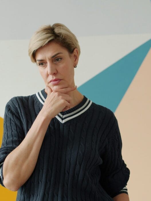 a woman with short blonde hair wearing a black sweater with a white collar