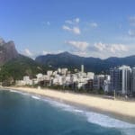 a beach with buildings and mountains in the background