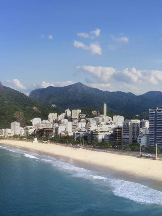 a beach with buildings and mountains in the background