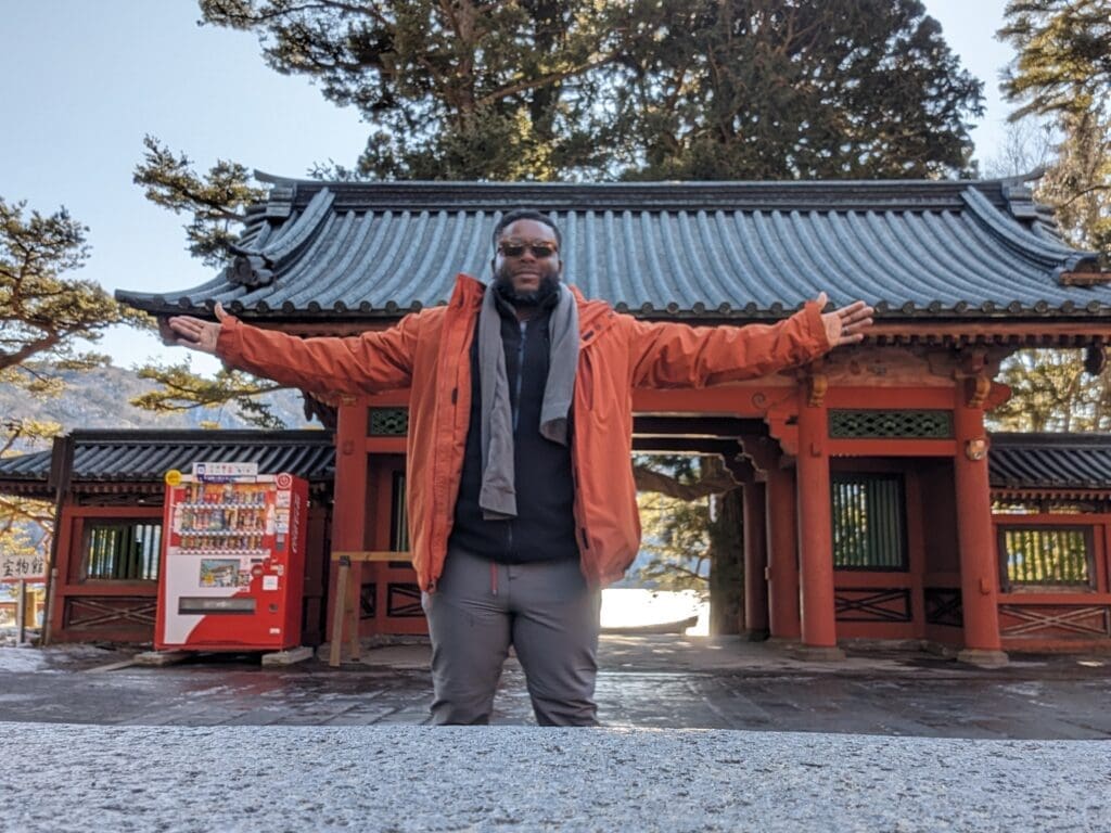a man standing in front of a building with his arms outstretched
