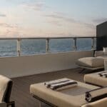 a deck with chairs and a railing overlooking the ocean