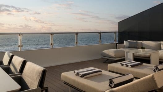 a deck with chairs and a railing overlooking the ocean