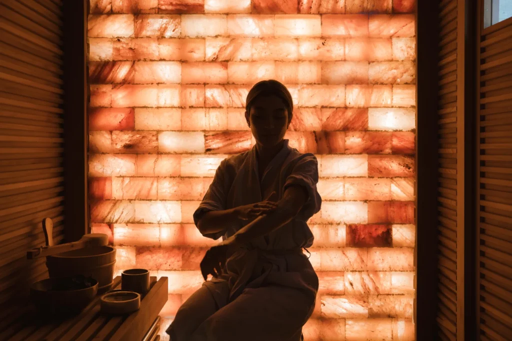 a woman in a bathrobe in a room with a wall of salt
