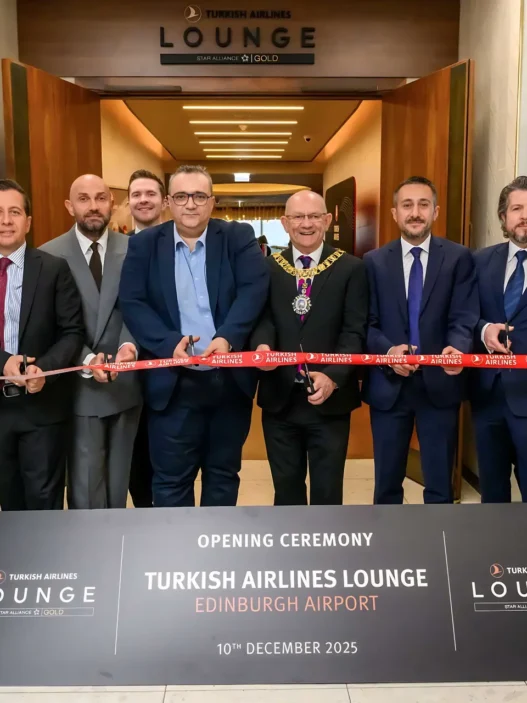 a group of people in suits cutting a red ribbon