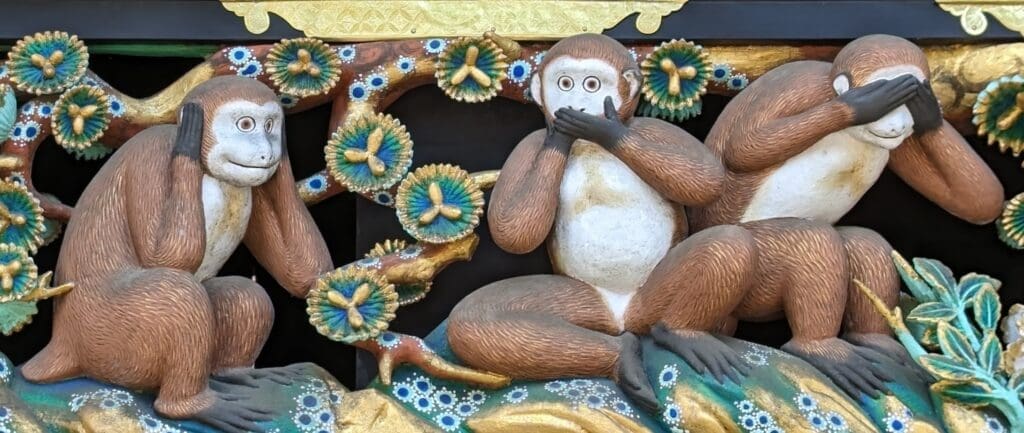 a statue of a monkey with hands covering its mouth