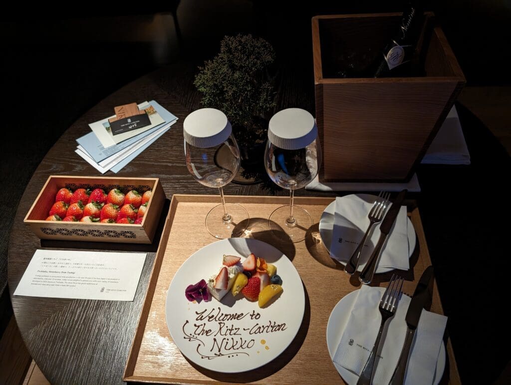 a table with a plate of fruit and wine glasses