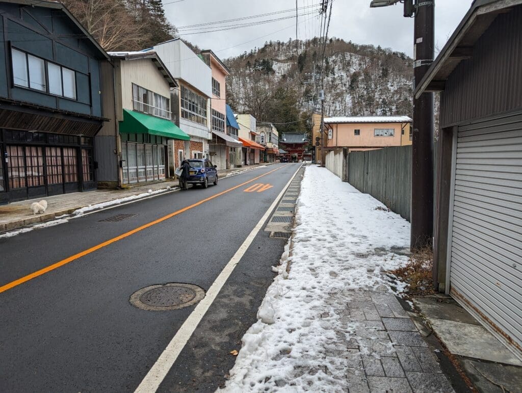 a snow covered street with buildings and a car