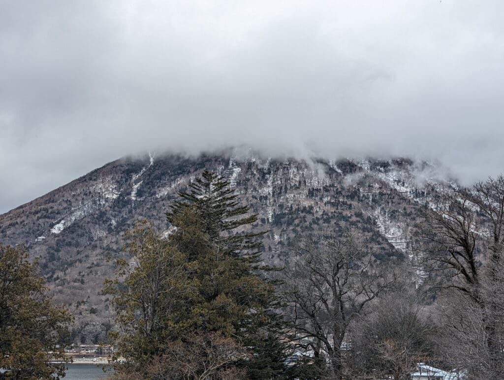 a mountain with trees and clouds