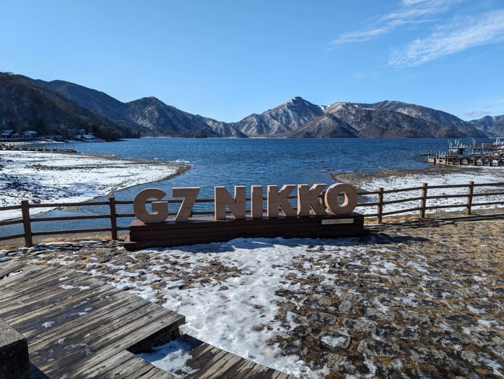 a sign with a lake and mountains in the background