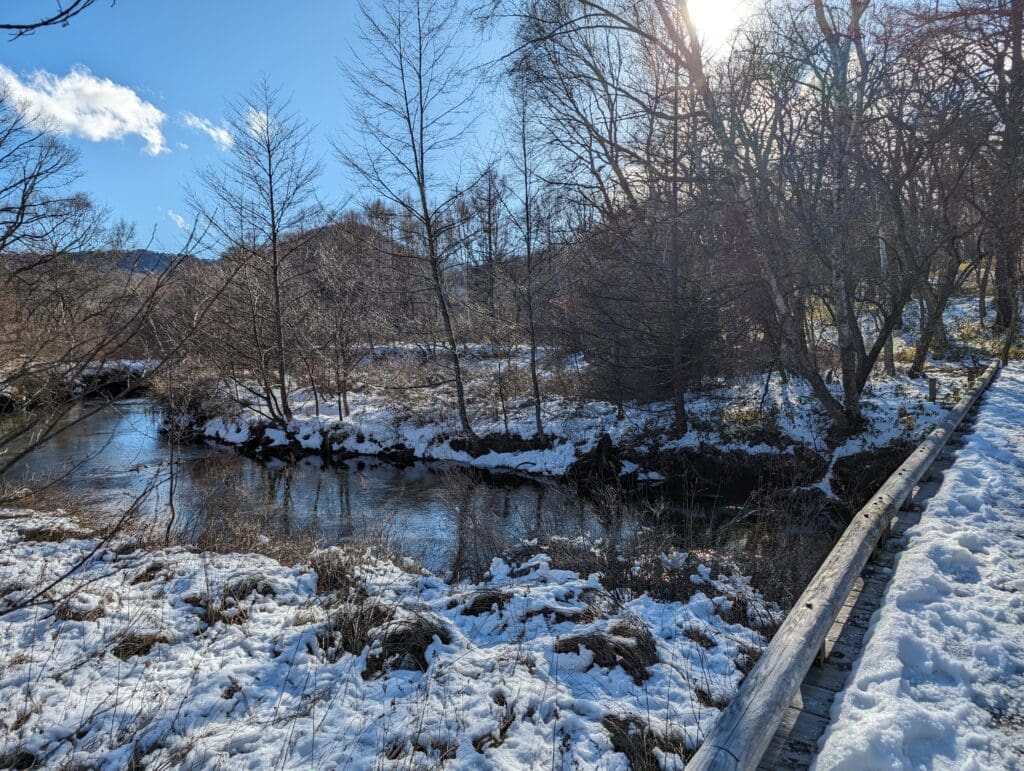 a snow covered river with a wooden bridge over it