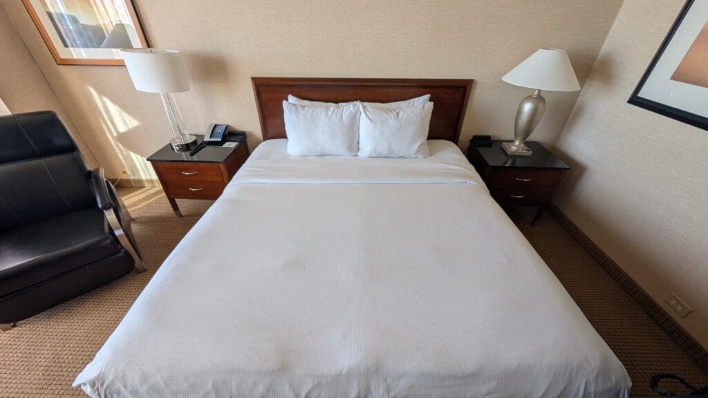 a bed with white sheets and lamps