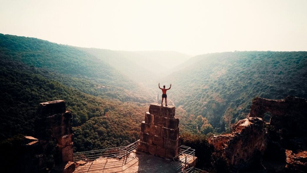a man standing on a stone tower with a valley in the background