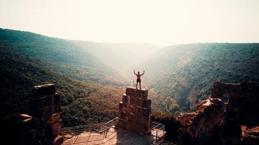 a man standing on a stone tower with a valley in the background
