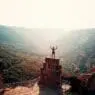 a man standing on a stone tower with a valley in the background
