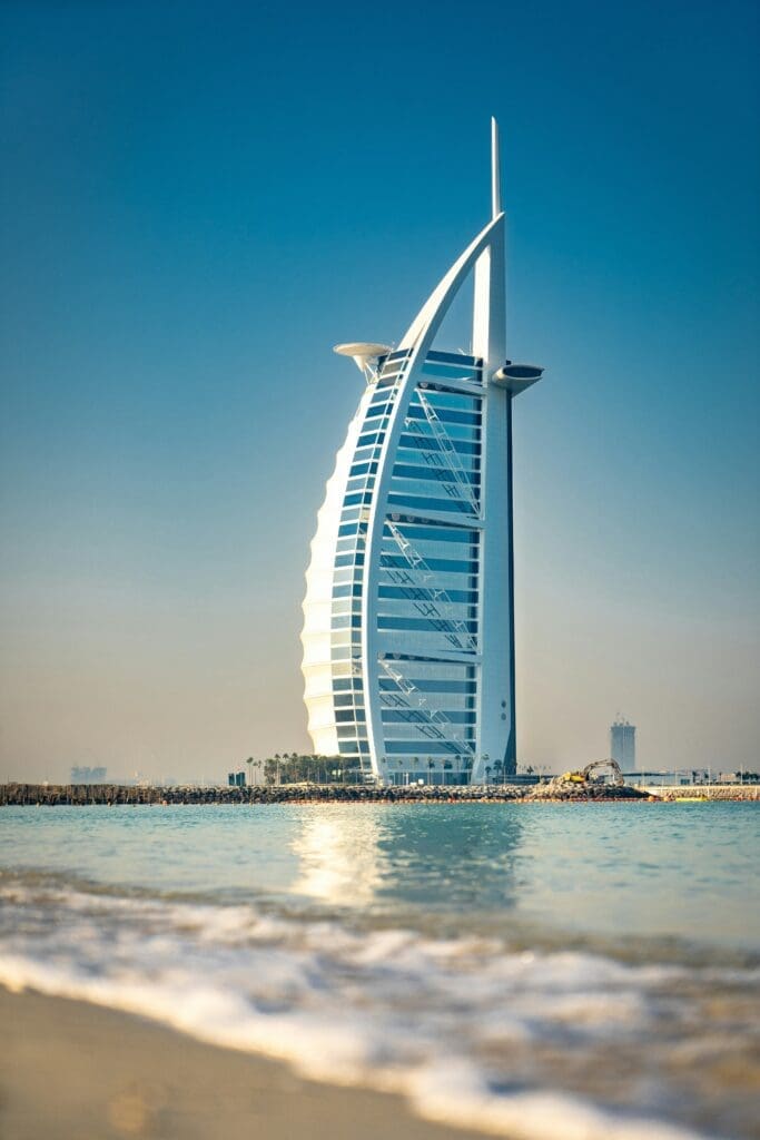 a tall building in the middle of a body of water with Burj Al Arab in the background