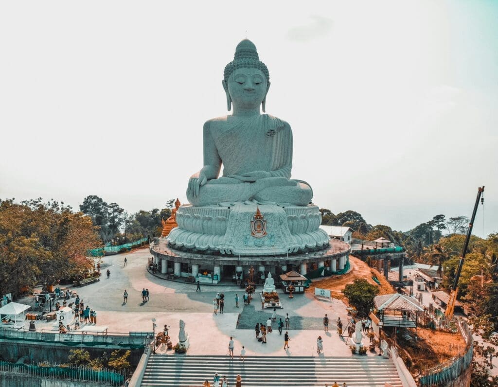 a large white statue of a buddha with Lantau Island in the background