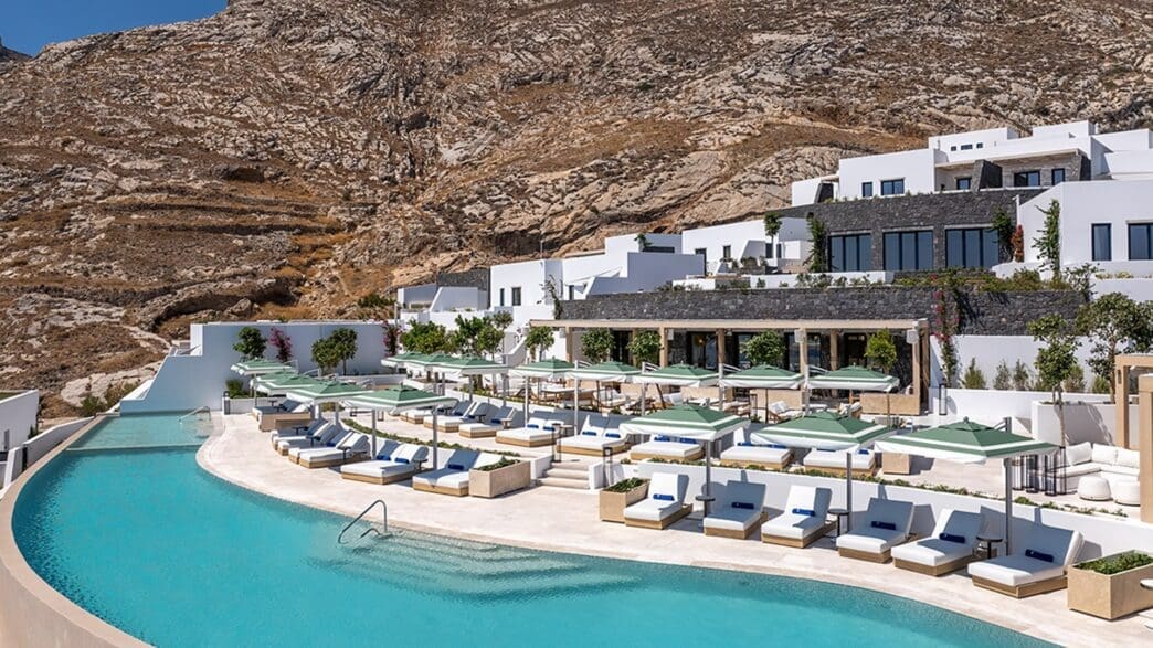 a pool with lounge chairs and umbrellas in front of a building