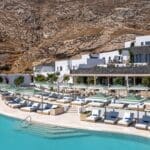 a pool with lounge chairs and umbrellas in front of a building