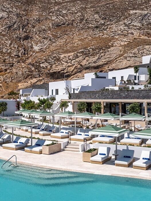 a pool with lounge chairs and umbrellas in front of a building