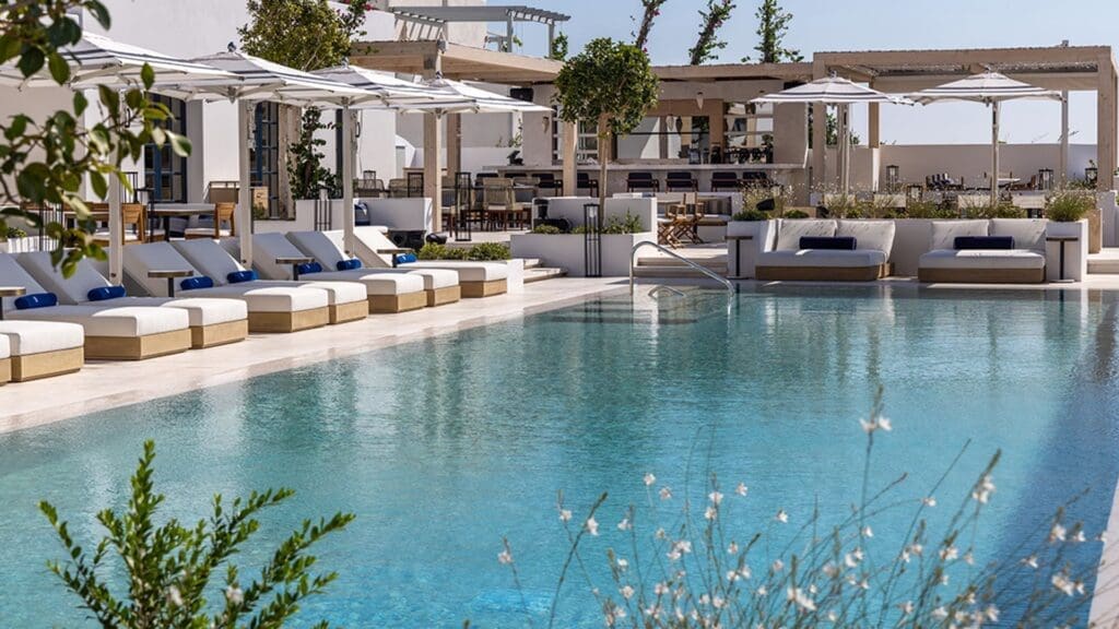 a swimming pool with white chairs and umbrellas