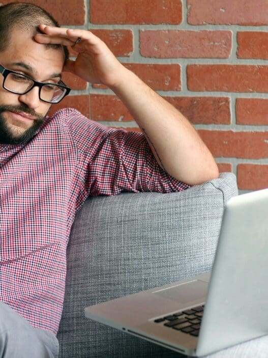 a man sitting on a couch with a laptop and phone
