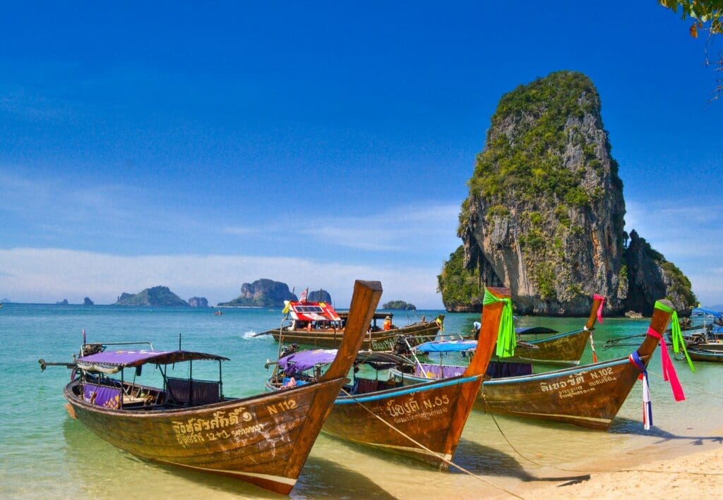 boats on the beach with a large rock in the background