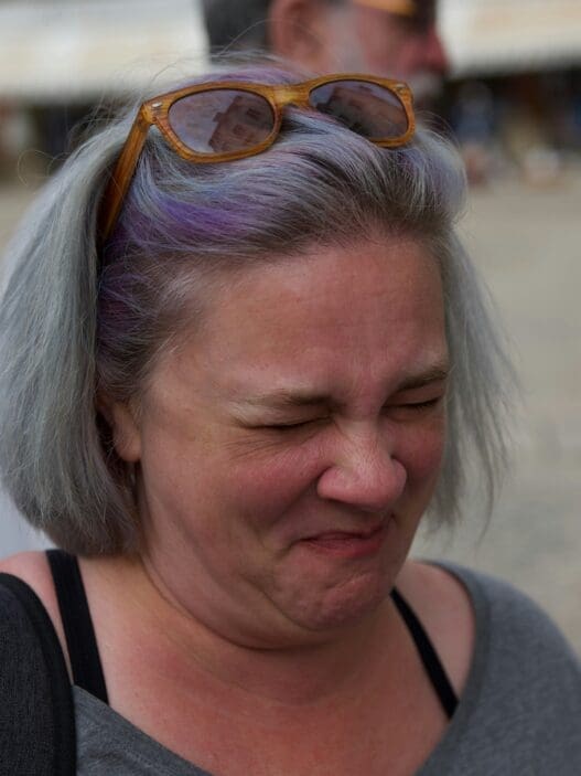 a woman with purple hair and sunglasses on her head