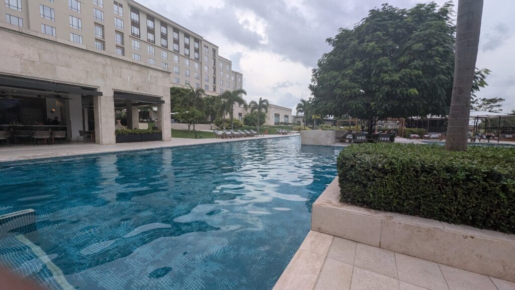 a pool with trees and bushes in front of a building