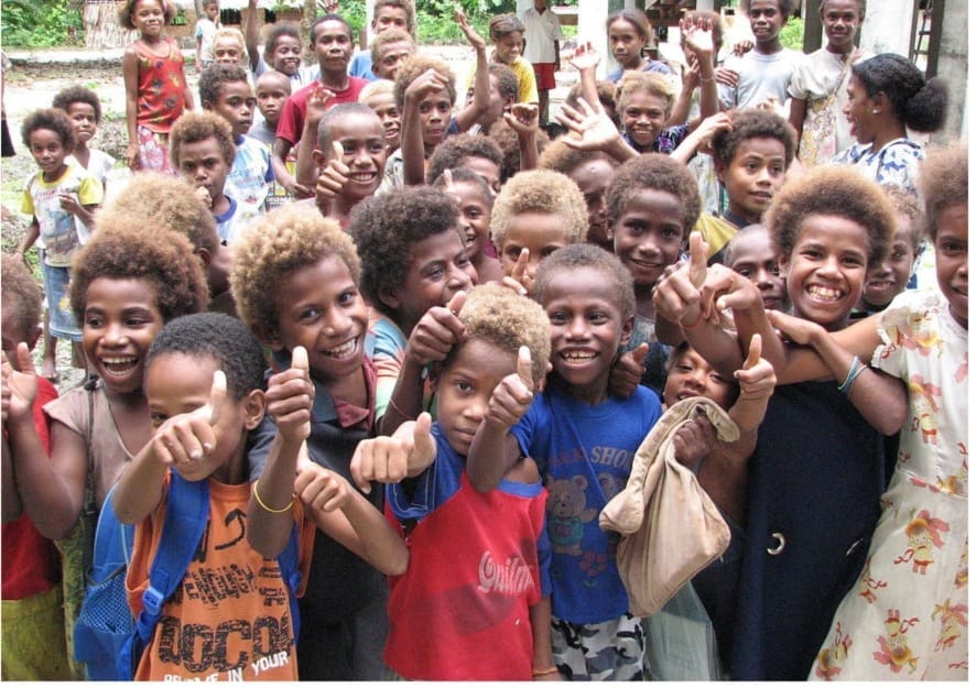 a group of children smiling and giving thumbs up