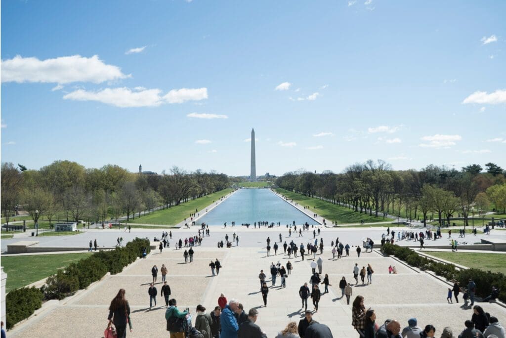 a group of people walking down a path with a monument in the background