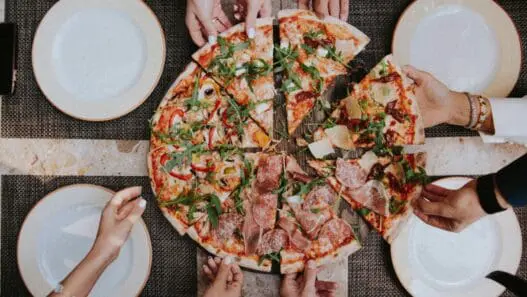 a group of people holding slices of pizza