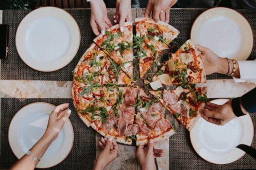 a group of people holding slices of pizza
