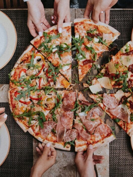 a group of people holding slices of pizza