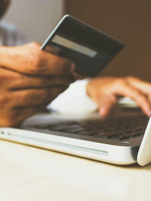 a person holding a credit card and typing on a laptop