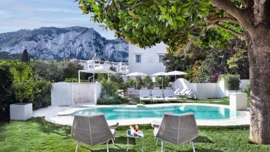 a pool with chairs and umbrellas in a backyard