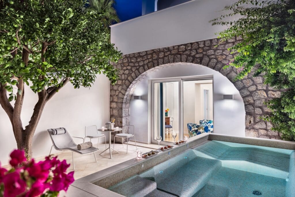 a pool with a stone arch and chairs