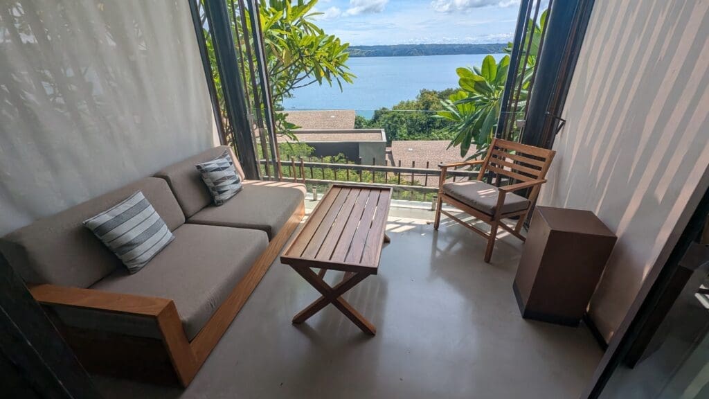 a couch and table with a view of the water from the balcony