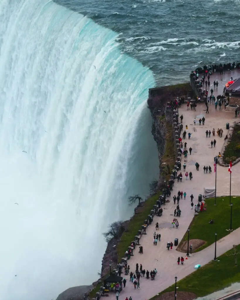a large waterfall with people walking on a path