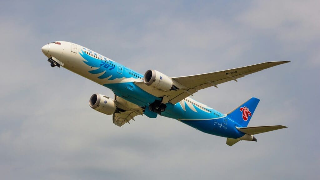 a blue and white airplane flying in the sky