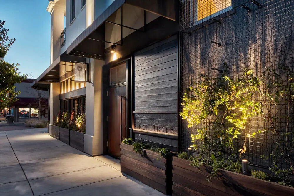 a sidewalk with plants in front of a building