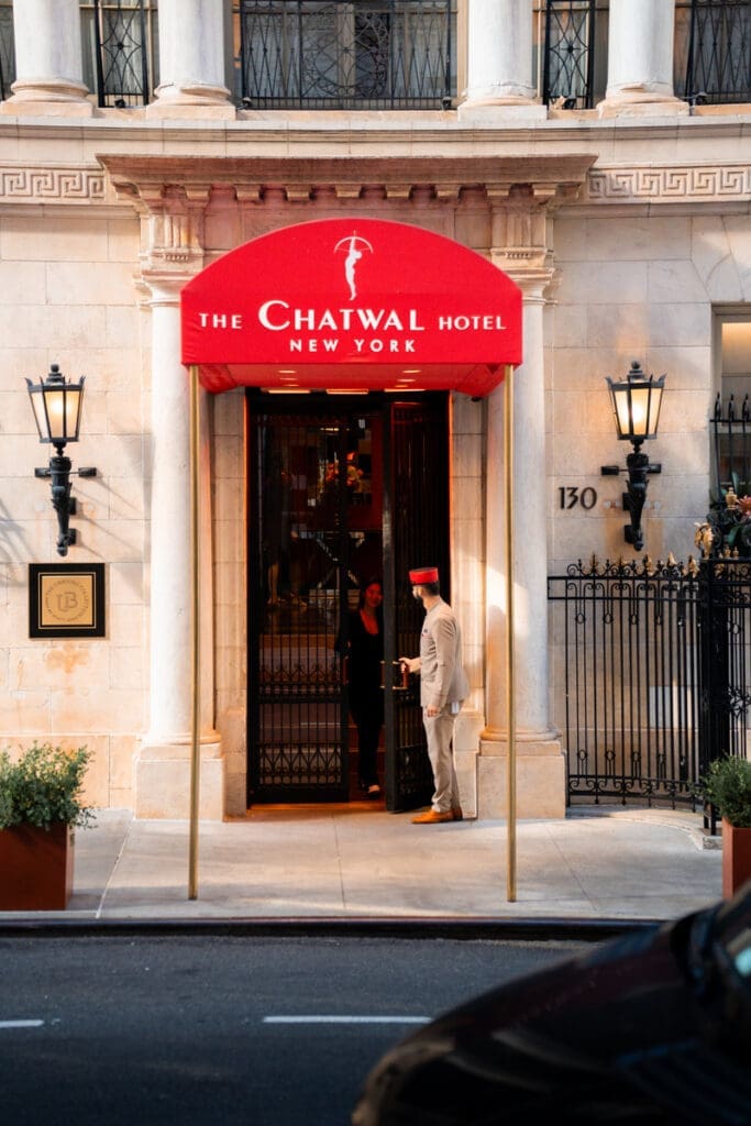 a man in a hat standing in front of a hotel entrance