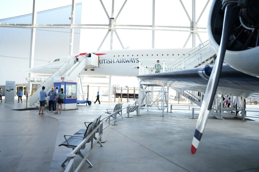 people standing in a hangar with a plane
