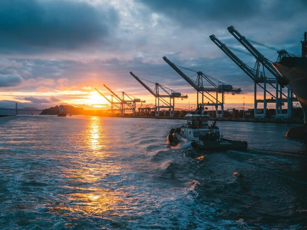 a boat in the water with cranes in the background